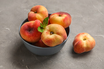 Bowl with sweet fig peaches and mint on grey background