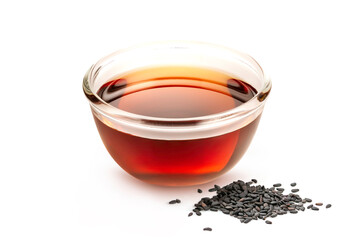 Sesame oil in glass with black sesame seeds isolated on white background.