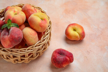 Naklejka na ściany i meble Wicker bowl with sweet fig peaches and mint on pink background
