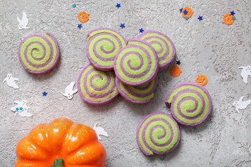 Tasty cookies with Halloween confetti and pumpkin on grunge grey background