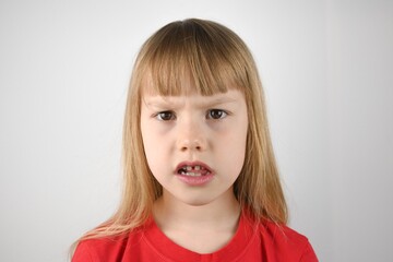 Naklejka premium Portrait of a little girl in a red T-shirt. The girl is in thought.