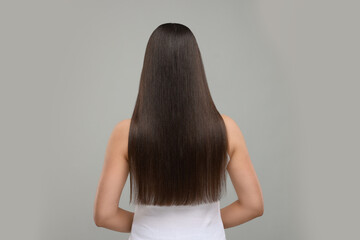 Woman with healthy hair after treatment on light grey background, back view