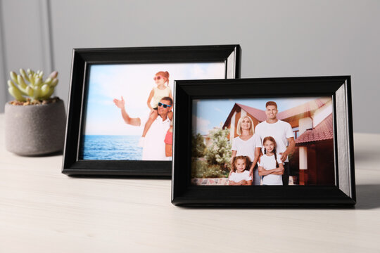 Frames with family photos and houseplant on white wooden table