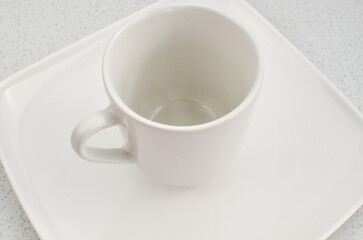 Obraz na płótnie Canvas Closeup of an empty high quality china cup on a white plate, a perfect match.