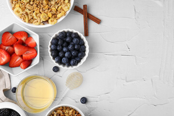 Tasty oatmeal, honey and fresh berries on white textured table, flat lay with space for text. Healthy breakfast