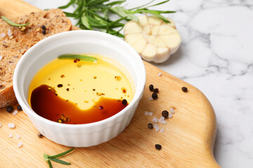 Bowl of organic balsamic vinegar with oil, bread slices and spices on white marble table, closeup. Space for text