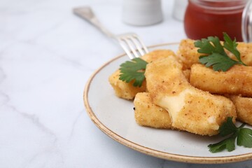 Plate with tasty fried mozzarella sticks and parsley on white marble table, closeup. Space for text
