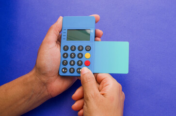 Hands holding a portable contactless payment device, An ultra-light and modern credit card next to the device. Finance and payments concept, ideal for fast and convenient transactions.