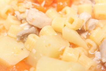 Chicken soup made with pasta, potatoes, tomatoes and chicken. Chicken soup with selective focus. soup prepared for the meal.