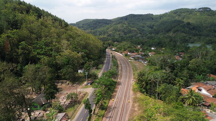 Fototapeta na wymiar Aerial drone view of highway and railroad tracks among green trees and mountains