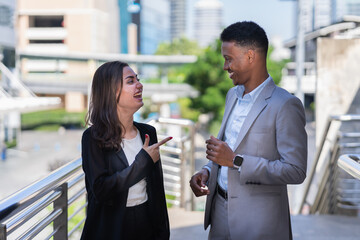 caucasian businesswoman in black suit happy talking with businessman. women and black man standing outside building in city