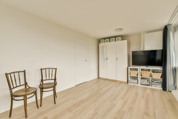 Fototapeta premium a living room with two chairs and a flat screen tv on the wall in the corner of the room is white