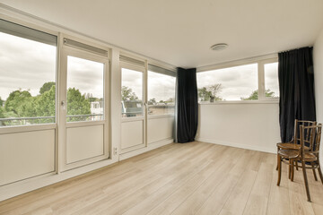 an empty room with wood flooring and large windows that look out onto the trees in the distance are cloudy skies