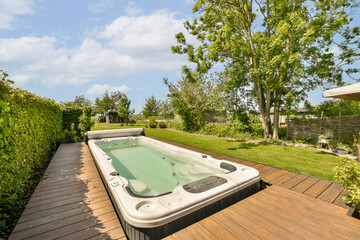 a hot tub on a wooden deck in the backyard with green trees and bushes surrounding it is clear blue...