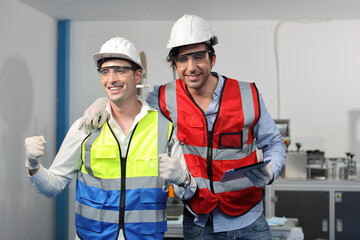 Caucasian mechanic technician maintenance, repairing industrial machinery equipment in factory. Professional worker in protective clothing with computer and mask using wrench at manufacturing factory
