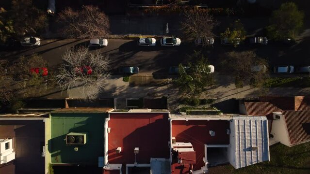 Cinematic top-down aerial turning overhead of the house and the road, a beautiful parallel of the house to the road, the roofs are separated