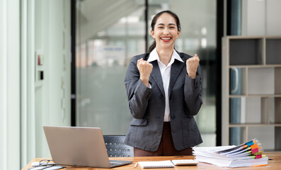 Excited businesswoman standing at her desk office