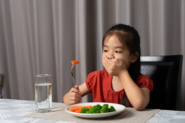 Little cute kid girl refusing to eat healthy vegetables. Children do not like to eat vegetables.