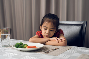 Little cute kid girl refusing to eat healthy vegetables. Children do not like to eat vegetables.