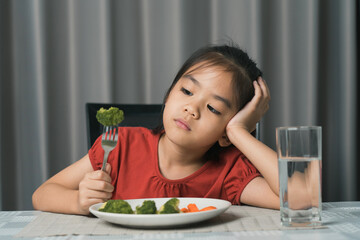 Little cute kid girl refusing to eat healthy vegetables. Children do not like to eat vegetables.