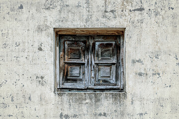 Fototapeta na wymiar Closed window with wooden shutters on the wall of an old house