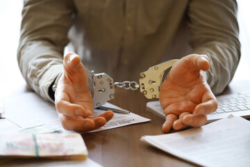 Hands in handcuffs behind, holding five thousand rubles. Concept of corruption