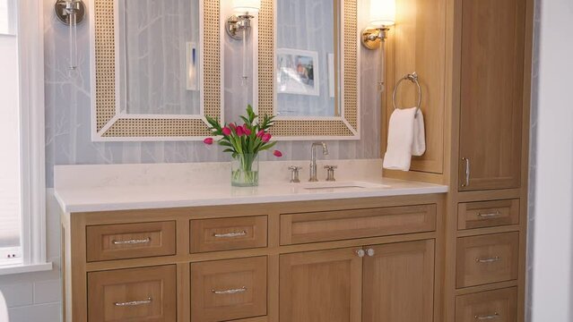 Primary bathroom sink with light brown cabinets, white countertop, and bright finishes