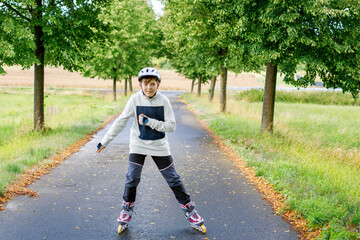 Active school boy skating in summer park, healthy lifestyle for children. Happy teenager with...