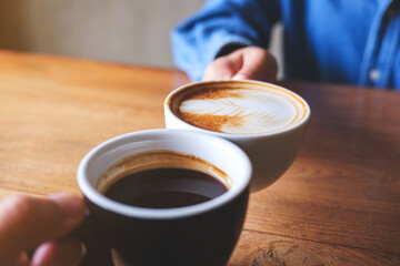 Closeup image of a couple people clinking coffee cups together in cafe