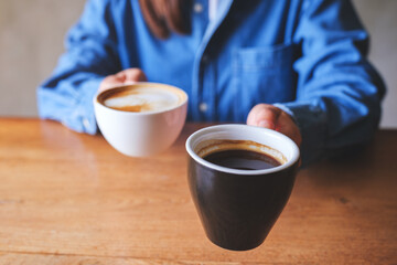 Closeup image of a woman holding and serving two cups of hot coffee