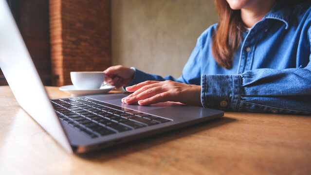 Closeup image of a woman drinking coffee while working on laptop computer
