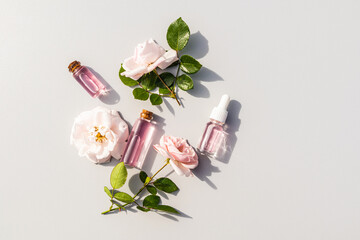 Several different glass cosmetic bottles with serum with bud flower rose extract and rose water for...