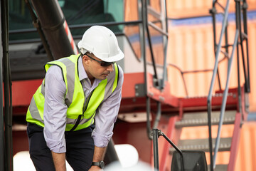 Logistic foreman standing on forklift truck at container warehouse distribution. Export import business concept