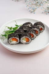 japanese sushi rolls with salmon and black sesame seeds on a whi