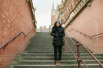 Woman laughing on the stairs at King's Cross Station in London, UK.