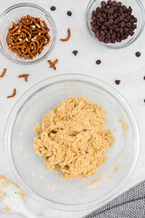 Cookie dough in bowl with pretzels and chocolate chips flatlay