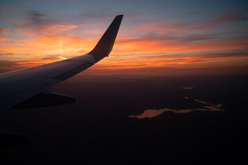 Sunset from airplane window seat view and body of water