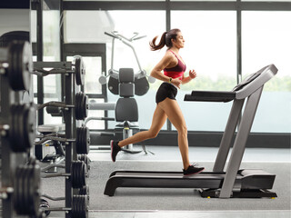 Fototapeta na wymiar Young woman exercising on a treadmill inside a gym
