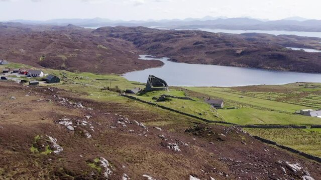 Drone shot circumnavigating the 'Dun Carloway Broch' on the west coast of the Isle of Lewis, part of the Outer Hebrides of Scotland. The mountains of the Isle of Harris are visible.
