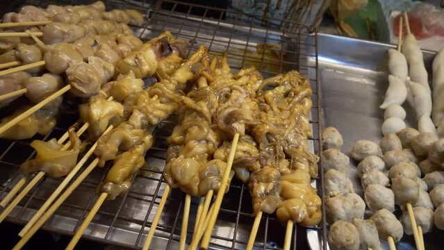 thailand night market street food booth pork organ in bamboo sticks ready to cook