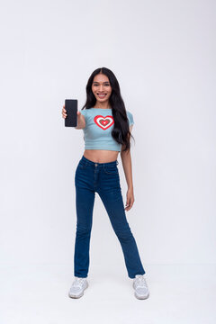 A young Filipino trans woman holding a cellphone. Whole body photo isolated on a white background.