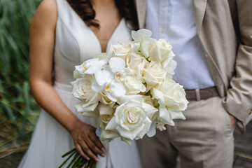 Obraz na płótnie Canvas Bride holding her wedding flower bouquet in her hands close-up