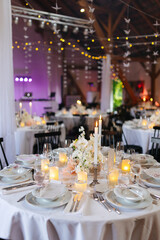 Beautiful table setting and decorations at a wedding. Wedding venue with beautiful decor, flowers, cutlery and lights