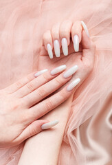 A woman's hands with a manicure on them, the nails are painted in a white color.