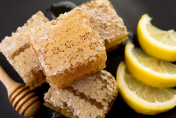 honeycomb and honey with fresh lemon on black background