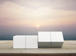Flipping of four white block cubes on wooden table over modern city tower and skyscraper at sunset,...