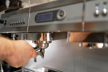 Close-up of barista cleans the portafilter before preparing the cappuccino in a coffee shop or restaurant.