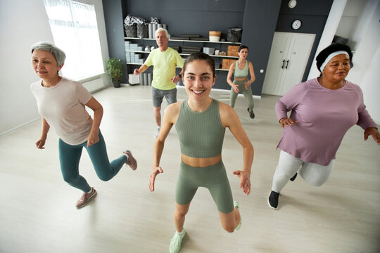 Elderly people dancing during training together with fitness instructor