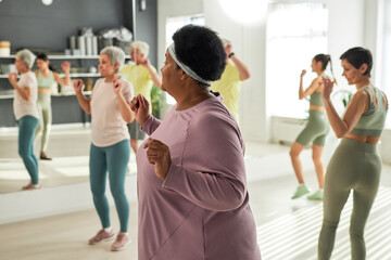 Group of elderly people exercising together in gym together with coach