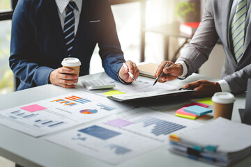 Young colleagues discuss business and analytical price charts using calculators and laptops to calculate financial, tax, accounting, statistics and analytical research ideas..